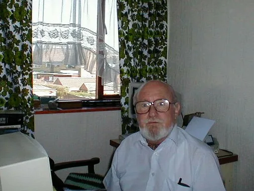 Alfred J. Askin at his desk, with the window and rooftops of Derby behind him